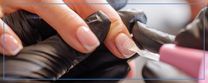 A Nail Technician putting a gloss coating on a customer's fingernail.