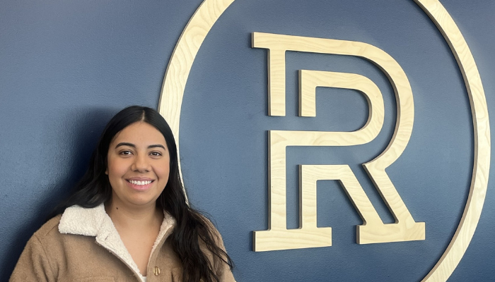 Mariana Lemus Lara-2024 standing by the wall Riverland with Logo