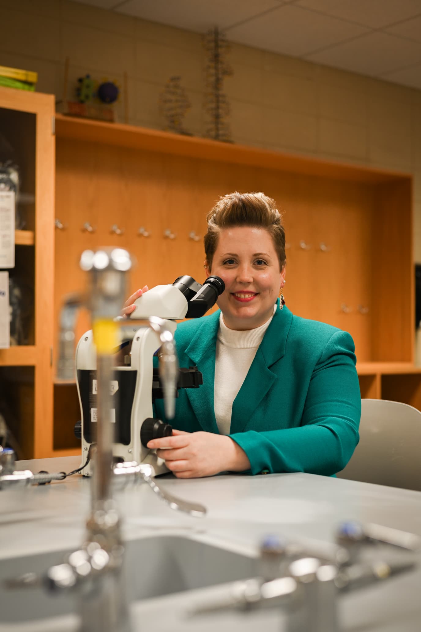 Image of Sadie Burkow in a green coat at a chem lab desk.