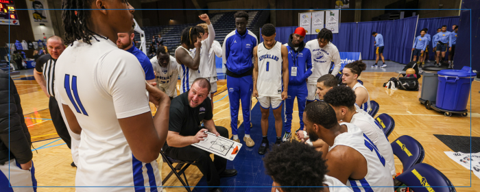 College basketball coach discussing strategy with players during a timeout