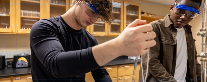 Students wearing safety goggles conducting an experiment in a science laboratory