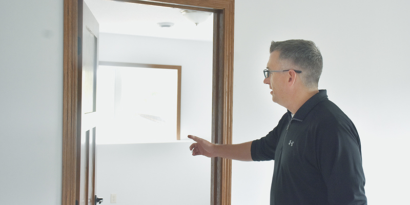 Man pointing toward a partially frosted glass door inside a room